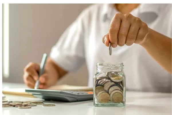 homem colocando moedas em um pote de vidro, e calculando.